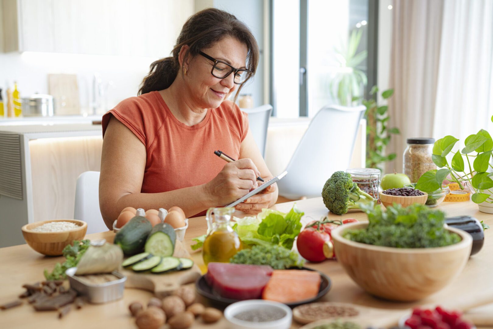 Woman writing at table with healthy food.