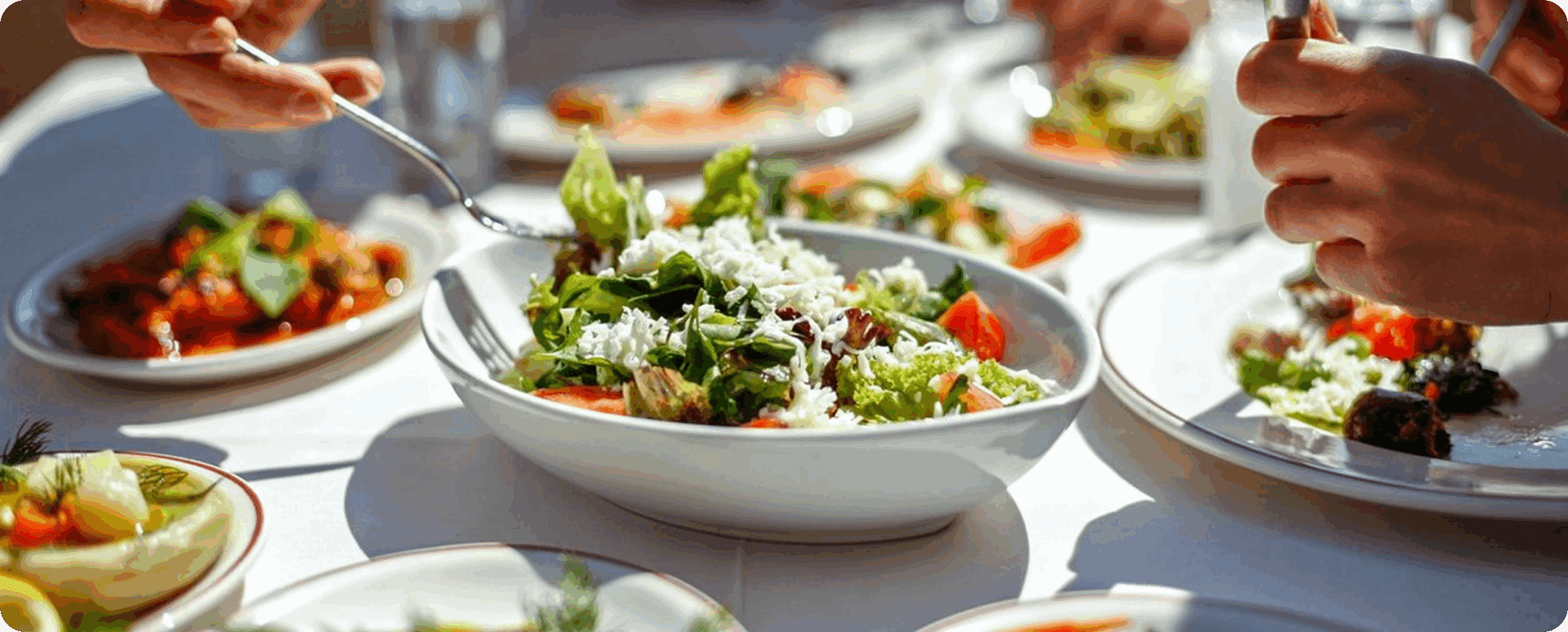 People enjoying a meal with fresh salads.